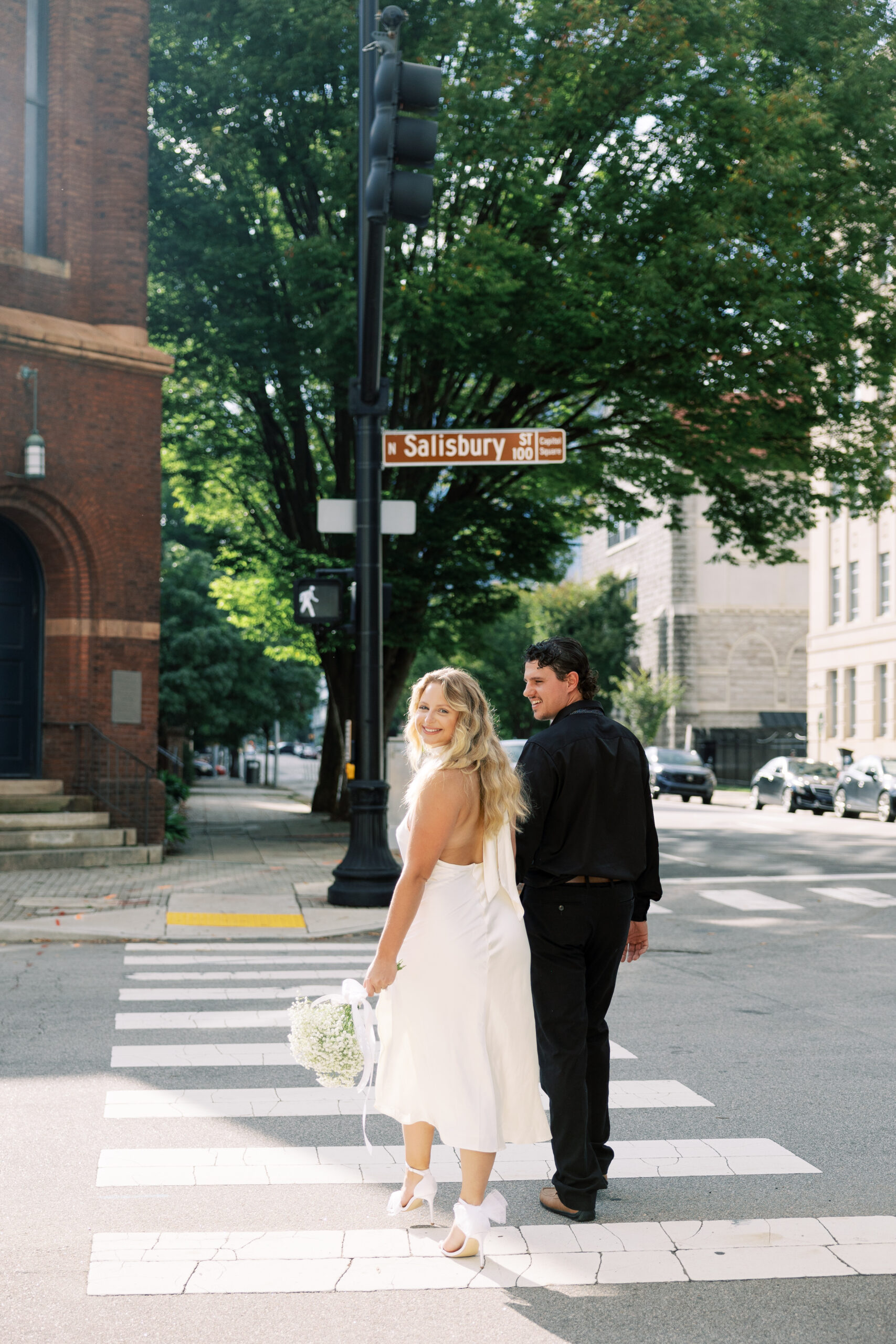 Couple crossing the street at Raleigh engagement session captured by Raleigh wedding photographers in downtown.