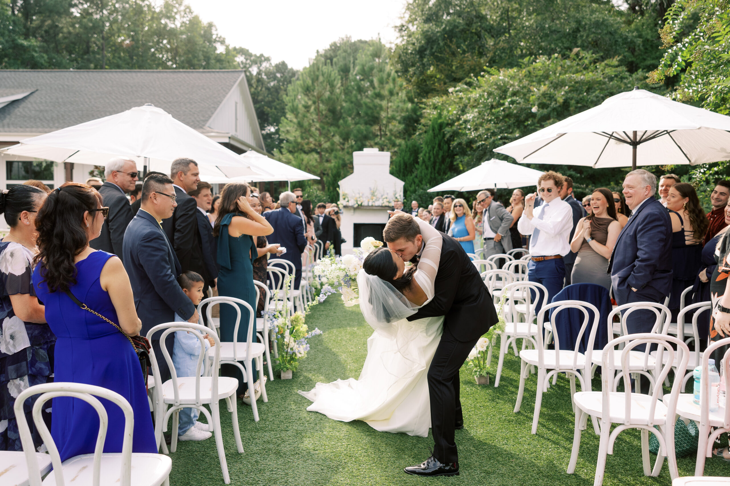 Bride and groom kissing in front of The Bradford North Carolina Wedding Venue, showcasing elegant wedding attire and timeless love.