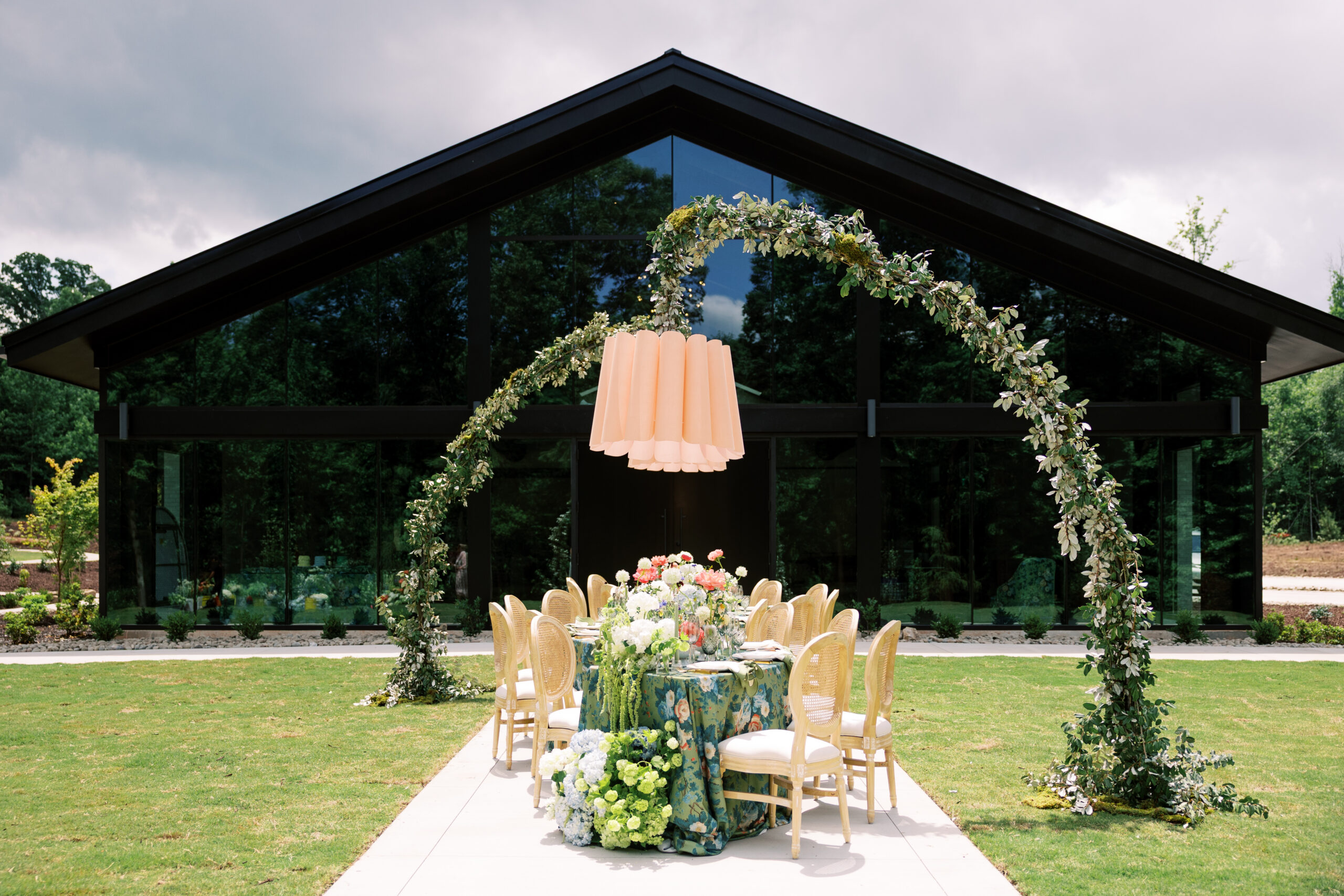 Curved floral-filled reception tables at The Skyroom wedding North Carolina against the modern black-glass building, captured by a Raleigh wedding photographer